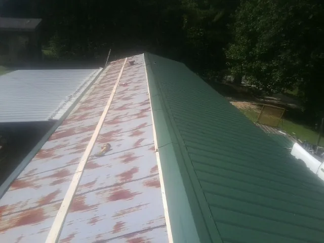 Old rusted panels beside newly installed green metal roofing — Wind Damage Roof Repair by Roofing Brothers in Roselle