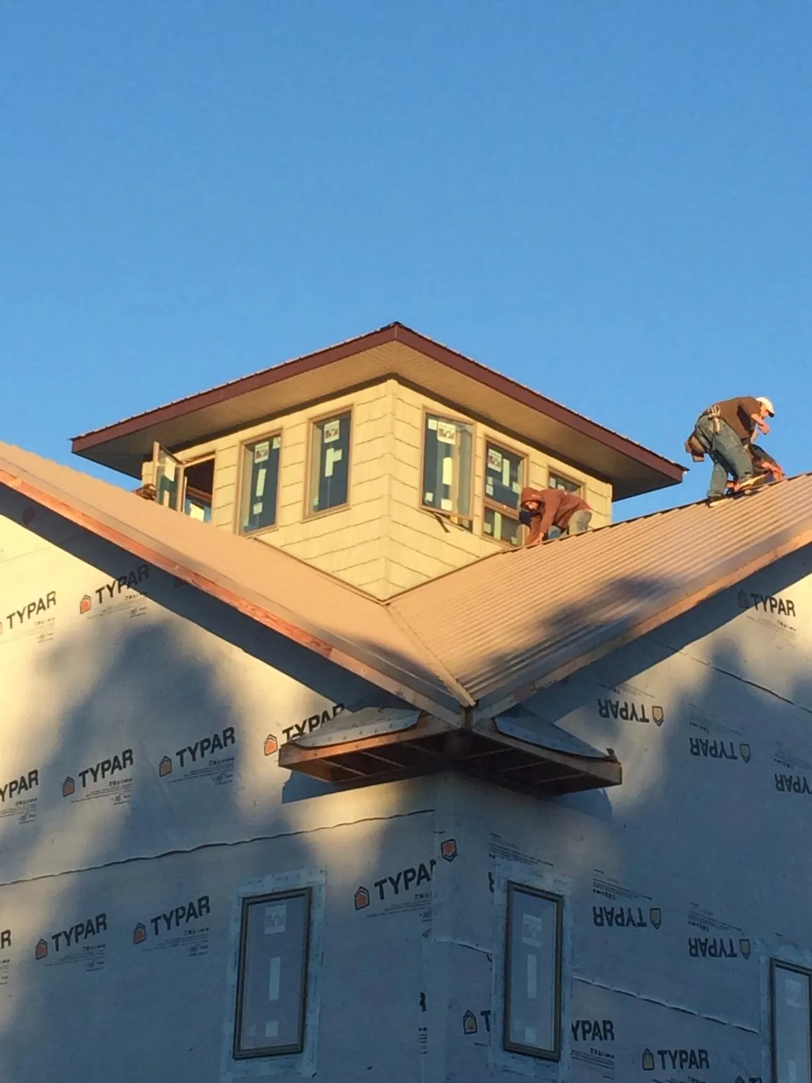 Roofers working around a rooftop cupola on a new metal roof at sunset — Roof Waterproofing in Roselle by Roofing Brothers